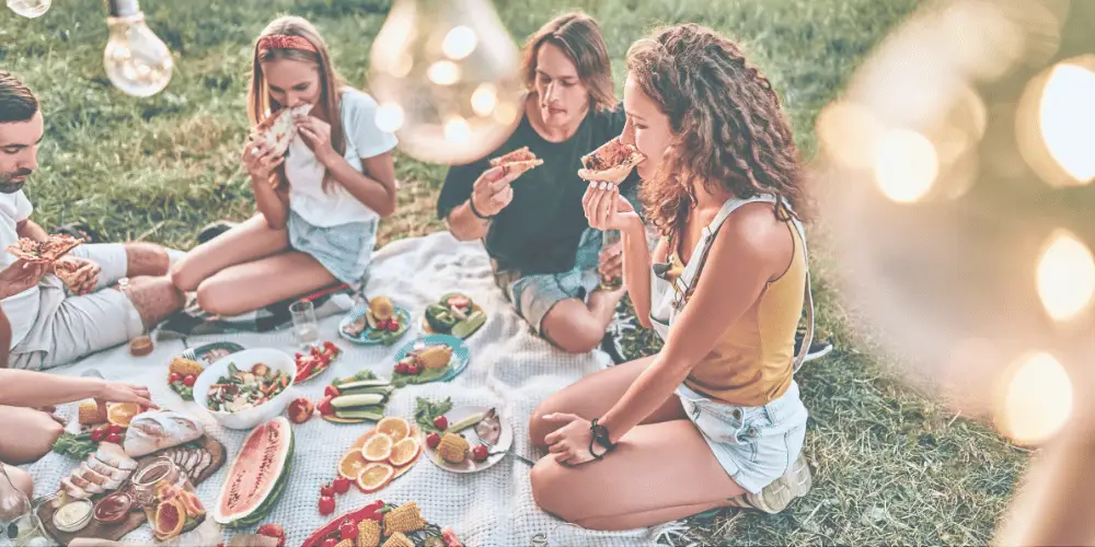 Freunde geniessen ein sommerliches Picknick im Freien mit passenden Weinen und feinen Speisen.