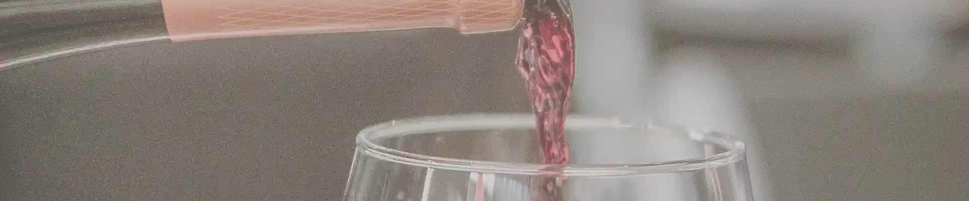 Nahaufnahme von Rotwein, der in ein Glas geschenkt wird.